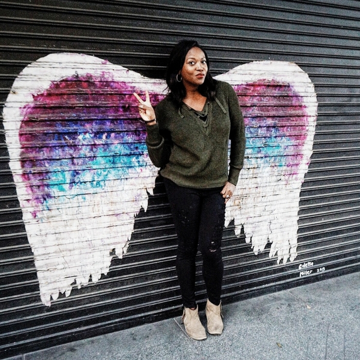 Stylist Melissa Chataigne posing with Angel wings street mural at in dtla fashion district in lace up sweater